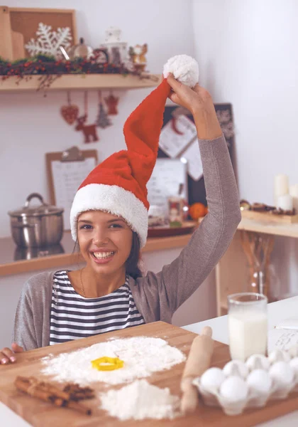 Lykkelig ung kvinde smilende glad for at have det sjovt med juleforberedelser iført Santa hat - Stock-foto