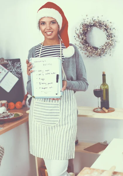 Felice giovane donna sorridente divertirsi con preparazioni di Natale indossando il cappello di Babbo Natale — Foto Stock