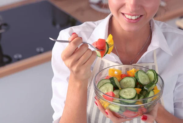 Mujer joven comiendo ensalada fresca en la cocina moderna — Foto de Stock