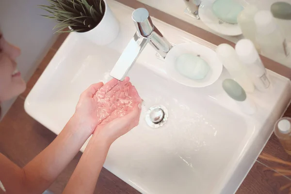 Jeune femme se lave le visage avec de l'eau propre dans la salle de bain — Photo