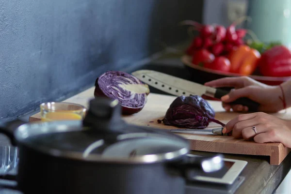 Mujer joven cortando verduras en la cocina de pie cerca del escritorio — Foto de Stock