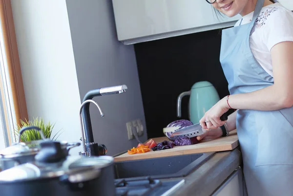 Giovane donna che taglia verdure in cucina in piedi vicino alla scrivania — Foto Stock