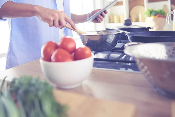 Человек по рецепту на цифровой планшет и приготовление вкусной и здоровой пищи на кухне в домашних условиях — стоковое фото