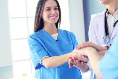 Doktorlar ve hemşireler tıbbi bir ekipte el ele tutuşuyorlar.