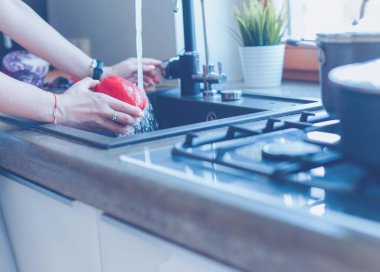 Sebze yıkayan kadın. Güzel genç bir kadın salata için sebze yıkıyor ve mutfakta dururken gülümsüyor.