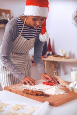 Mutlu genç bayan gülümsüyor Noel hazırlıklarıyla eğleniyor Noel Baba şapkası takıyor.