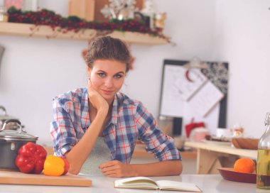 Mutfakta gülümseyen genç bir kadın, Noel arkaplanında soyutlanmış.