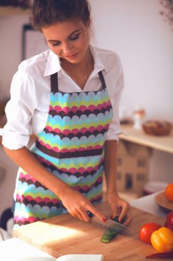 Gülümseyen kadın mutfakta salata hazırlıyor.