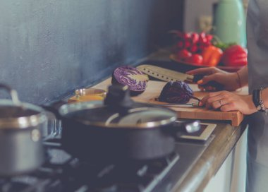 Masanın yanında duran mutfakta sebze doğrayan genç bir kadın.