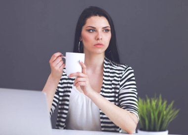 Gri arka planda dizüstü bilgisayarı olan genç bir kadın.