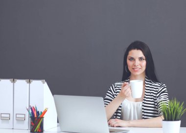 Gri arka planda dizüstü bilgisayarı olan genç bir kadın.