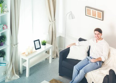 Genç adam sandalyede oturuyor ve dizüstü bilgisayarla çalışıyor.