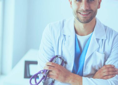 Genç ve kendinden emin erkek doktor portresi tıp ofisinde duruyor..