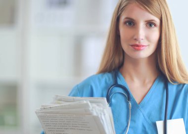 Hastane koridorunda klasörlü kadın doktor portresi.