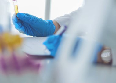 Kadın araştırmacı, beyaz arka planda izole edilmiş ilaç şişeleri ve mataralarla çevrili.