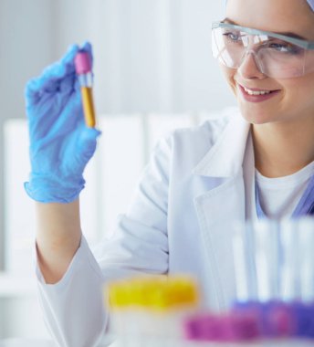 Laboratuvarda sıvı yeşil çözeltiye bakan bir tıbbi veya bilimsel araştırmacı ya da doktor