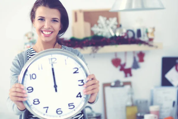 Happy young woman showing clock in christmas decorated kitchen — Stock Photo, Image