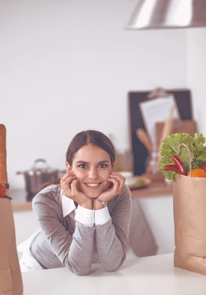 Young woman holding grocery shopping bag with vegetables Standing in the kitchen — Stock Photo, Image