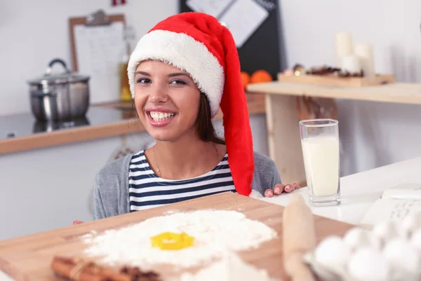 Kvinde i julemand hat gør jul cookies i køkkenet - Stock-foto