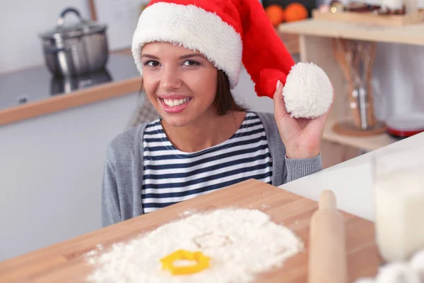 Donna in cappello di Babbo Natale fare biscotti di Natale in cucina — Foto Stock