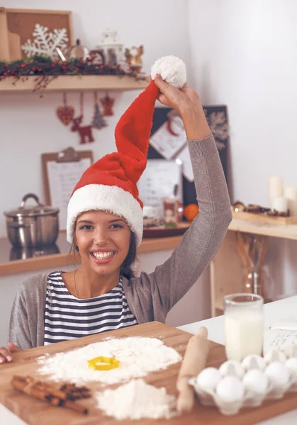 Woman in santa hat making christmas cookies in the kitchen — Stock Photo, Image