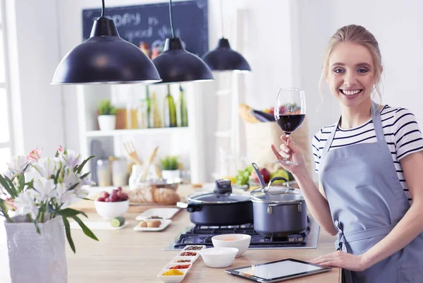 Mujer bonita bebiendo un poco de vino en casa en la cocina —  Fotos de Stock