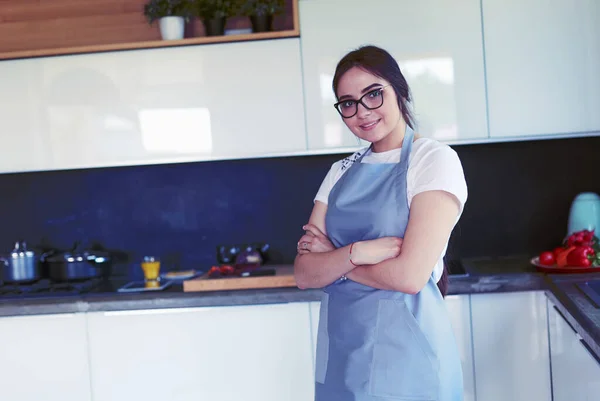 Porträt einer jungen Frau, die mit verschränkten Armen vor Küchenhintergrund steht — Stockfoto