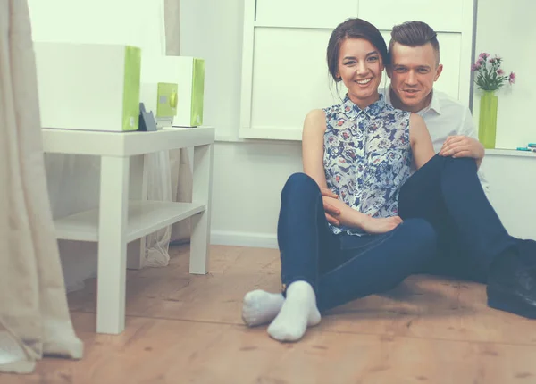 Feliz jovem casal sentado juntos no chão — Fotografia de Stock