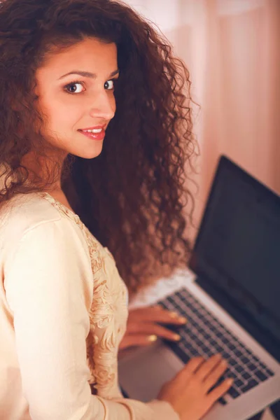 Eine junge Frau mit Laptop sitzt isoliert auf weißem Hintergrund — Stockfoto