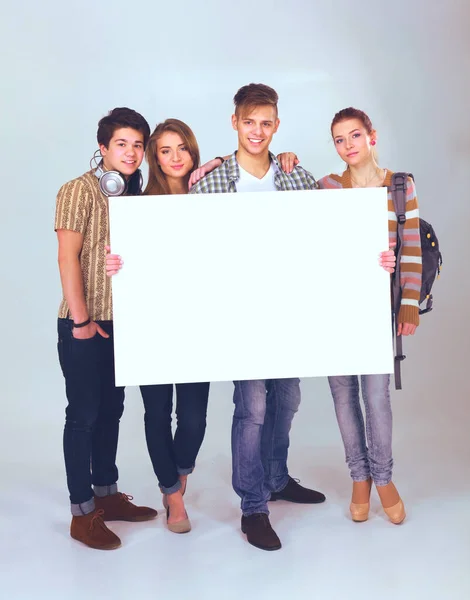 Group of young friends holding a blank board, isolated on white background — Stock Photo, Image