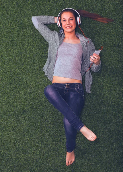 Donna rilassata ascoltando la musica con le cuffie sdraiato sull'erba — Foto Stock