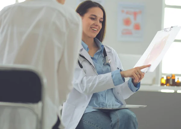 Arzt und Patient diskutieren etwas, während sie am Tisch sitzen. Medizin und Gesundheitskonzept — Stockfoto