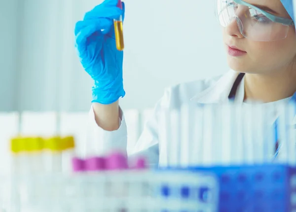 Una investigadora médica o científica o una doctora mirando un tubo de ensayo de una solución clara en un laboratorio — Foto de Stock