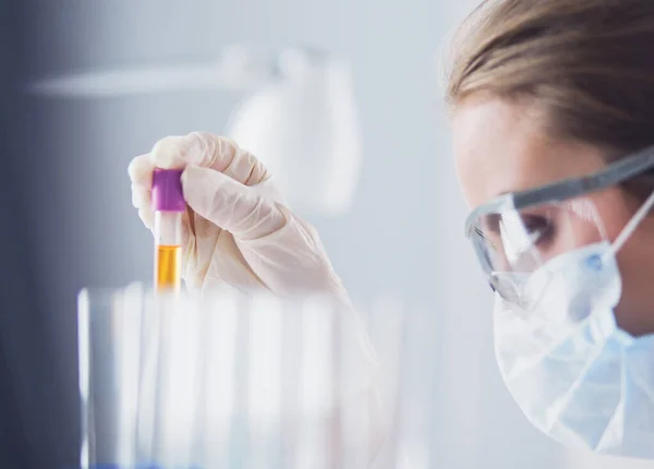 Un investigador médico o científico o un médico que observa un tubo de ensayo de solución verde líquida en un laboratorio — Foto de Stock