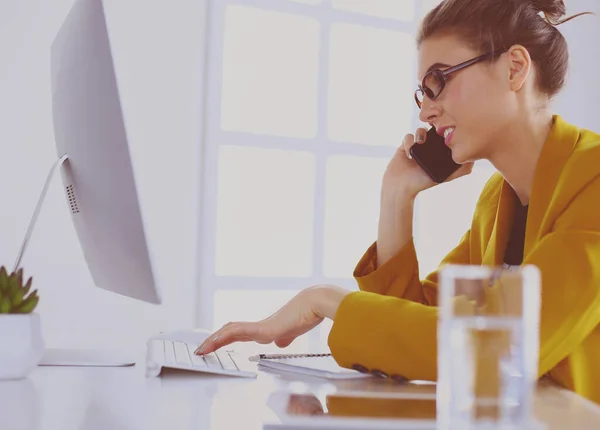 Retrato de mulher bonita fazendo chamada enquanto sentada em seu local de trabalho na frente do laptop e trabalhando em novo projeto — Fotografia de Stock