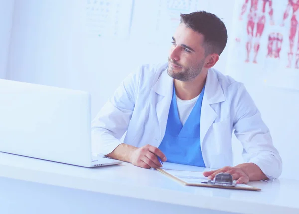 Portrait d'un médecin avec un ordinateur portable assis au bureau médical. — Photo