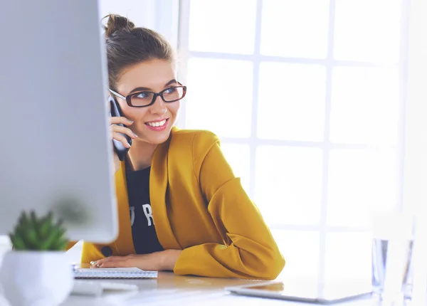 Businesswoman sitting in office with laptop on telephone — Stock Photo, Image