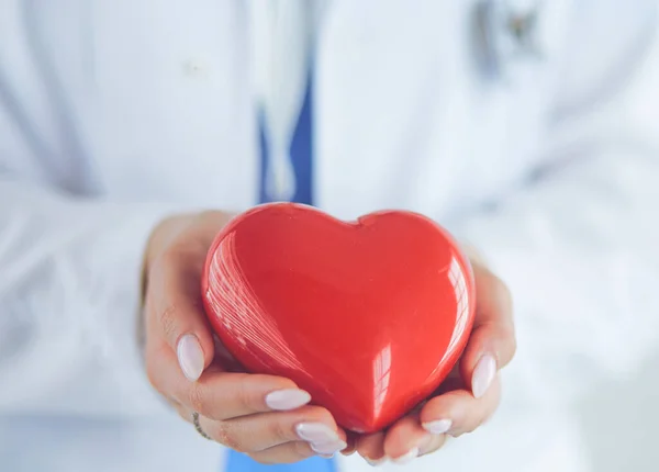 Female doctor with stethoscope holding heart, on light background — Stock Photo, Image