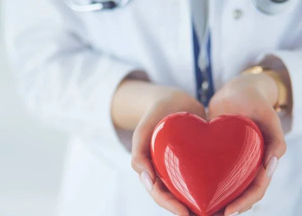 Female doctor with stethoscope holding heart, on light background — Stock Photo, Image