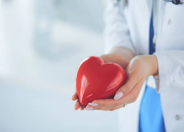 Médica com estetoscópio segurando coração, em fundo claro — Fotografia de Stock