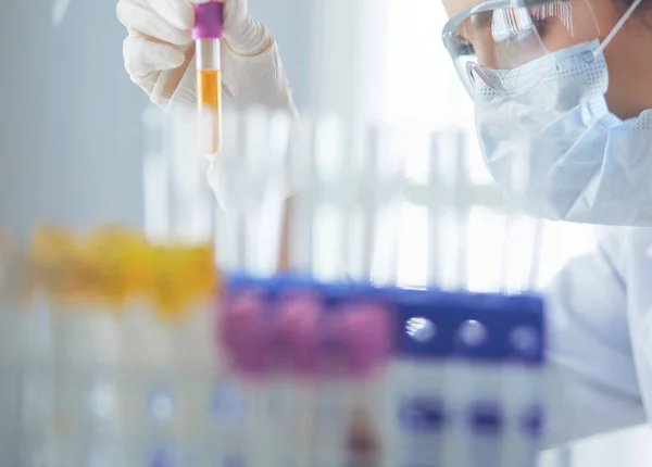 A medical or scientific researcher or doctor looking at a test tube of liquid green solution in a laboratory — Stock Photo, Image