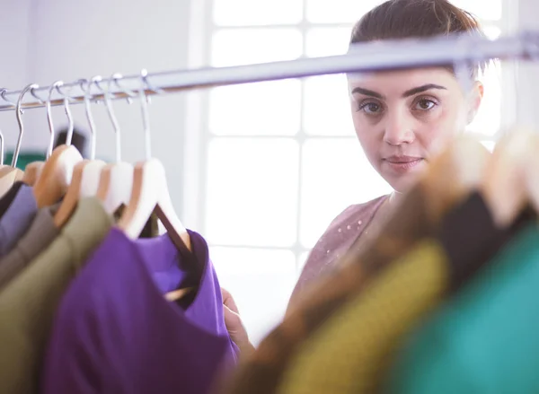 Mooie jonge stylist bij rek met hangers — Stockfoto