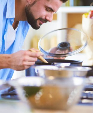 Dijital tablet ve yemek pişirme tarifine uyan bir adam evdeki mutfakta lezzetli ve sağlıklı yemekler pişiriyor.