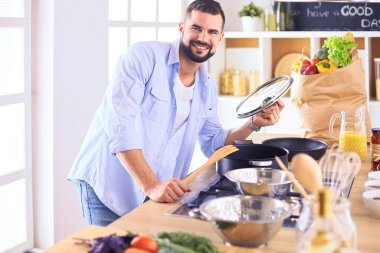 Dijital tablet ve yemek pişirme tarifine uyan bir adam evdeki mutfakta lezzetli ve sağlıklı yemekler pişiriyor.