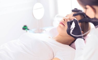 Güzellik salonunda kaş makyajı yapılan genç bir kadın.