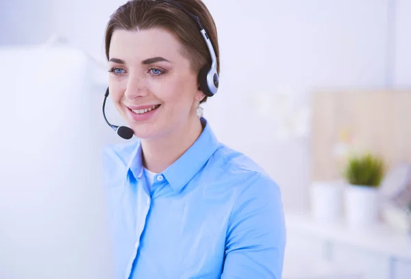 Ernstige mooie jonge vrouw die werkt als support telefoon operator met headset in het kantoor — Stockfoto