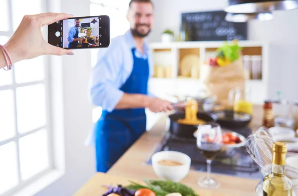 Uomo che prepara cibo delizioso e sano nella cucina di casa. Il suo video per il suo blog. — Foto Stock