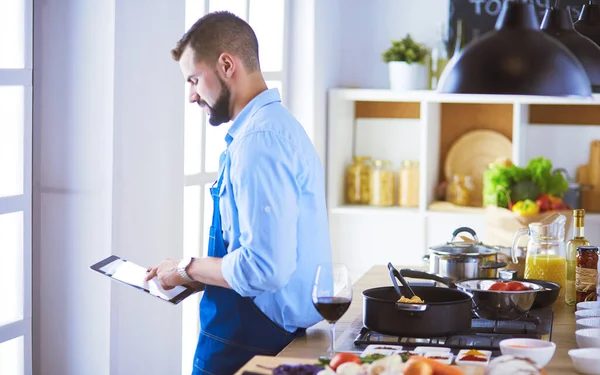 Man efter recept på digital tablett och matlagning välsmakande och hälsosam mat i köket hemma — Stockfoto