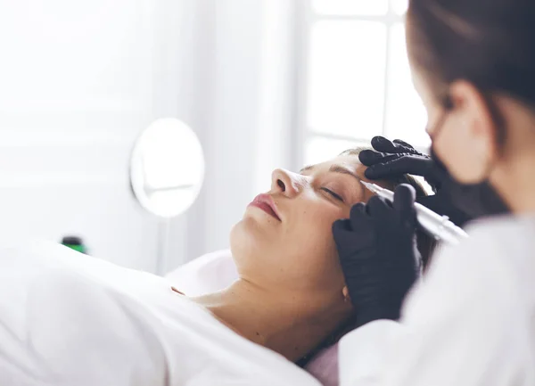 Mujer joven sometida a procedimiento de maquillaje permanente de cejas en salón de belleza —  Fotos de Stock