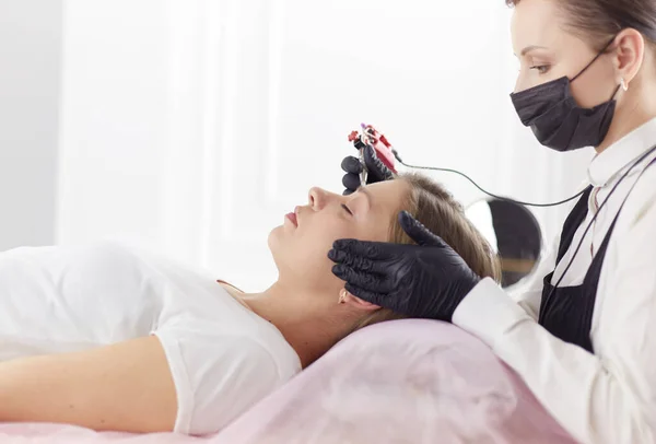 Cosmetólogo aplicando maquillaje permanente en las cejas —  Fotos de Stock